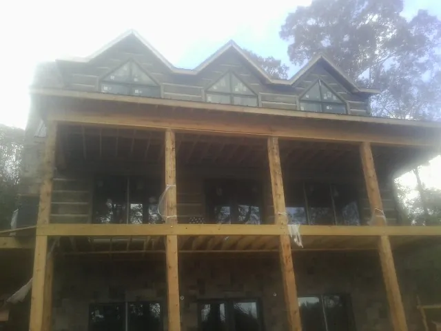 Dormers and porch framing on a large log home under construction — Roof Coating work by our crew in Dorset
